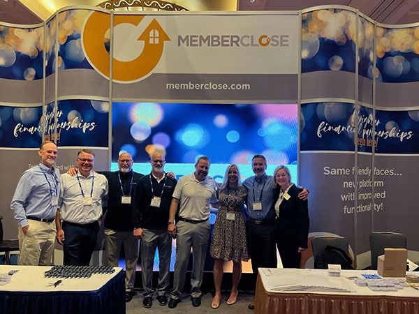 MemberClose team standing in conference booth